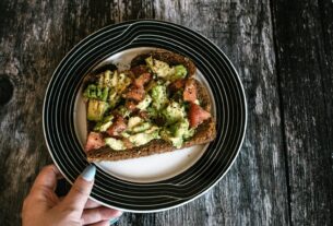 A slice of hearty avocado toast with tomatoes served on a stylish plate. Perfect for healthy eating.