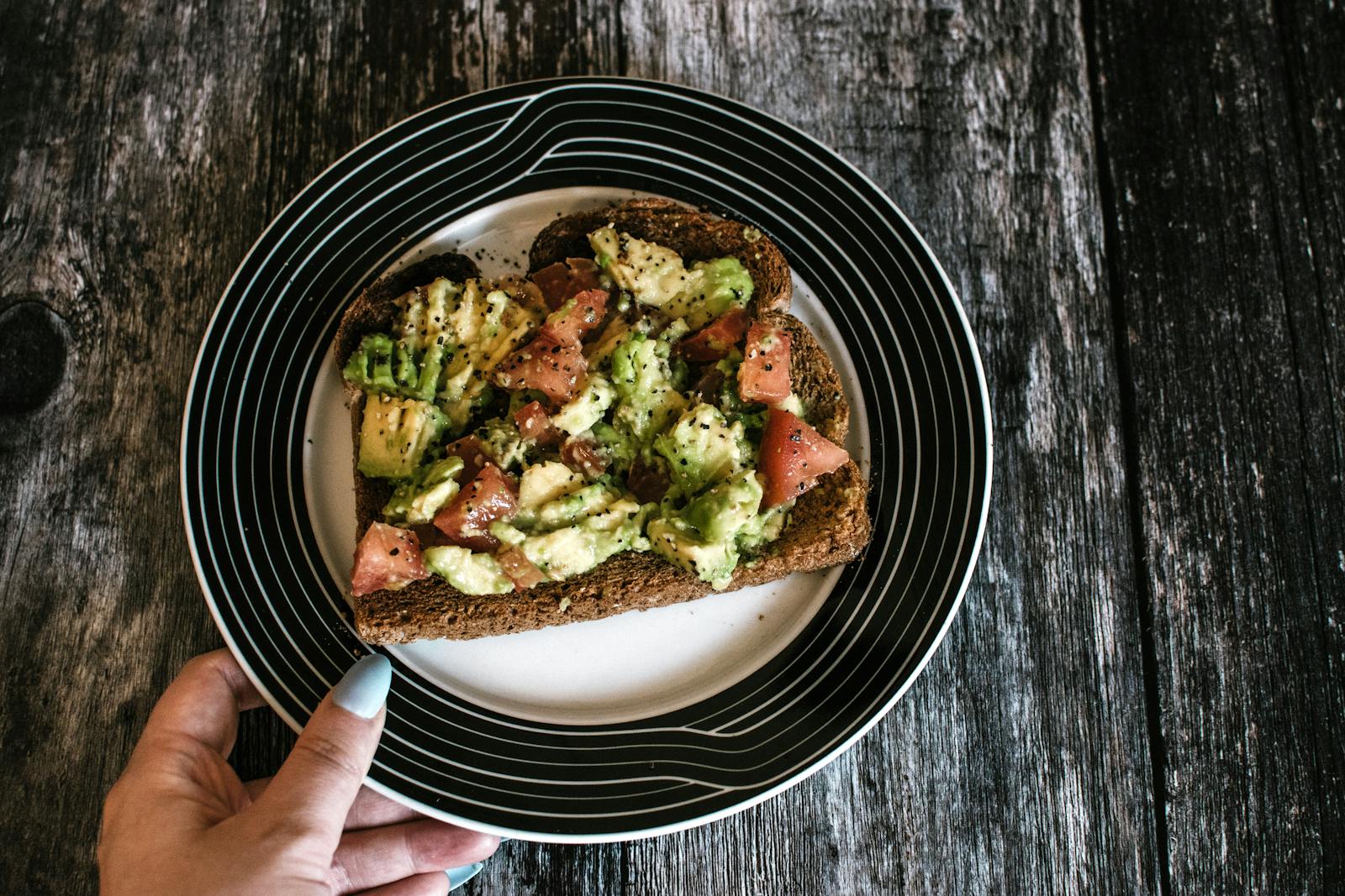 A slice of hearty avocado toast with tomatoes served on a stylish plate. Perfect for healthy eating.