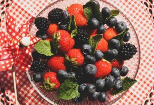 A vibrant mix of strawberries, blackberries, and blueberries with mint leaves in a glass bowl.