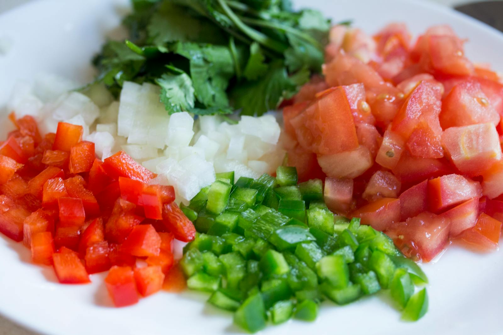 Colorful diced vegetables on a plate, perfect for healthy cooking and meal prep.