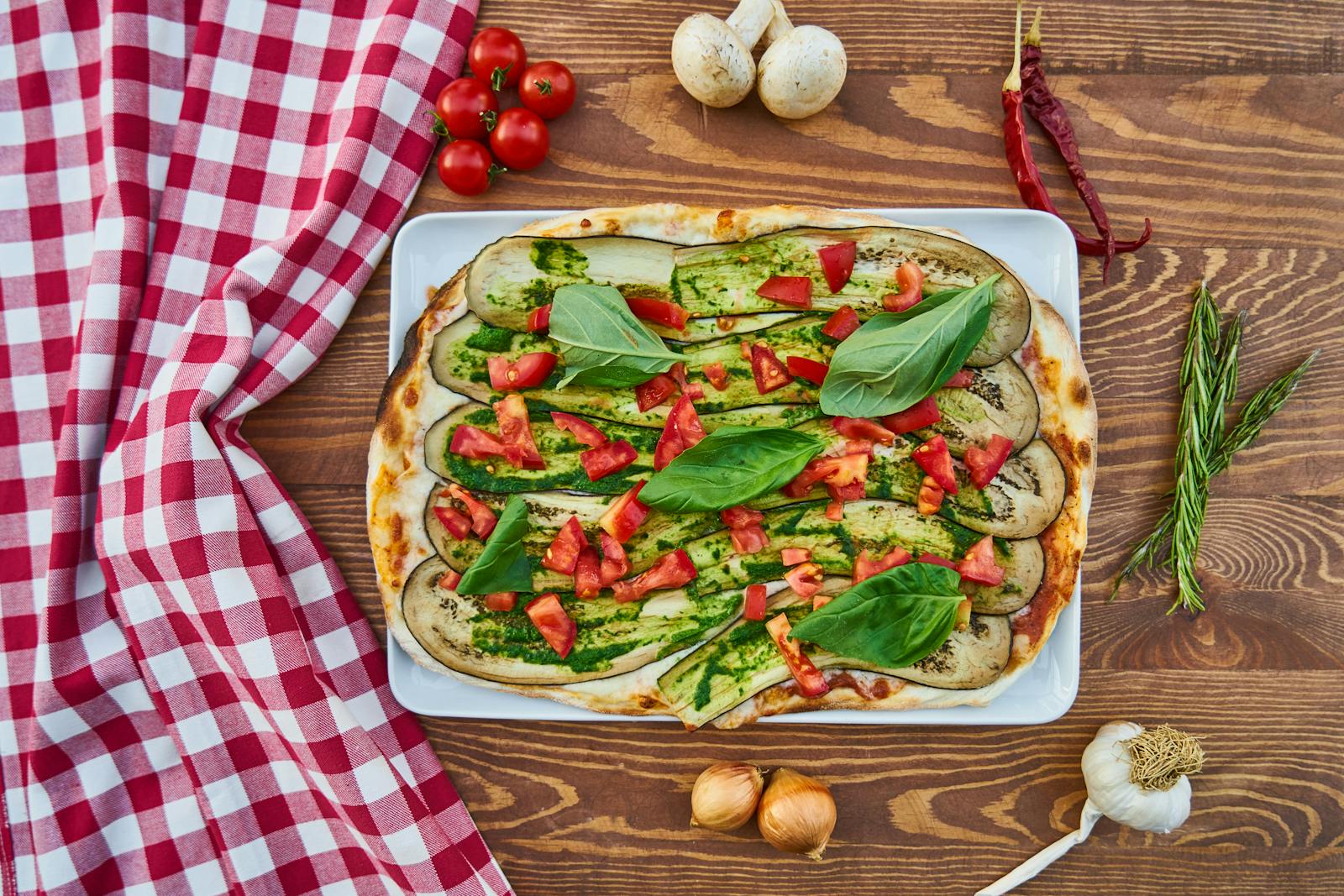 Delicious vegetable pizza with fresh basil, tomatoes, and eggplant, perfect for a healthy meal.