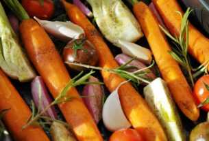 Colorful vegetables ready for baking, featuring carrots, tomatoes, and herbs.