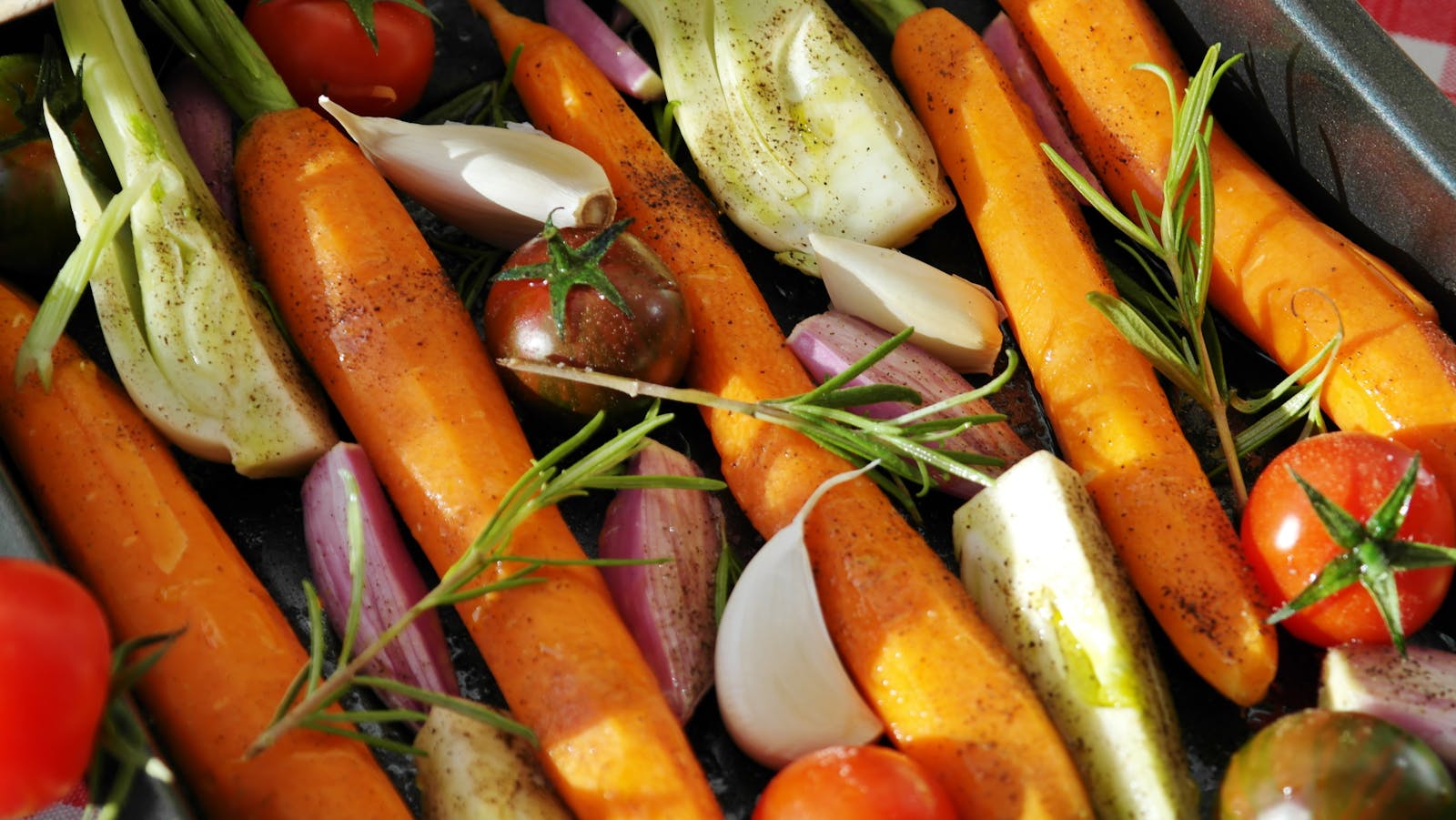 Colorful vegetables ready for baking, featuring carrots, tomatoes, and herbs.