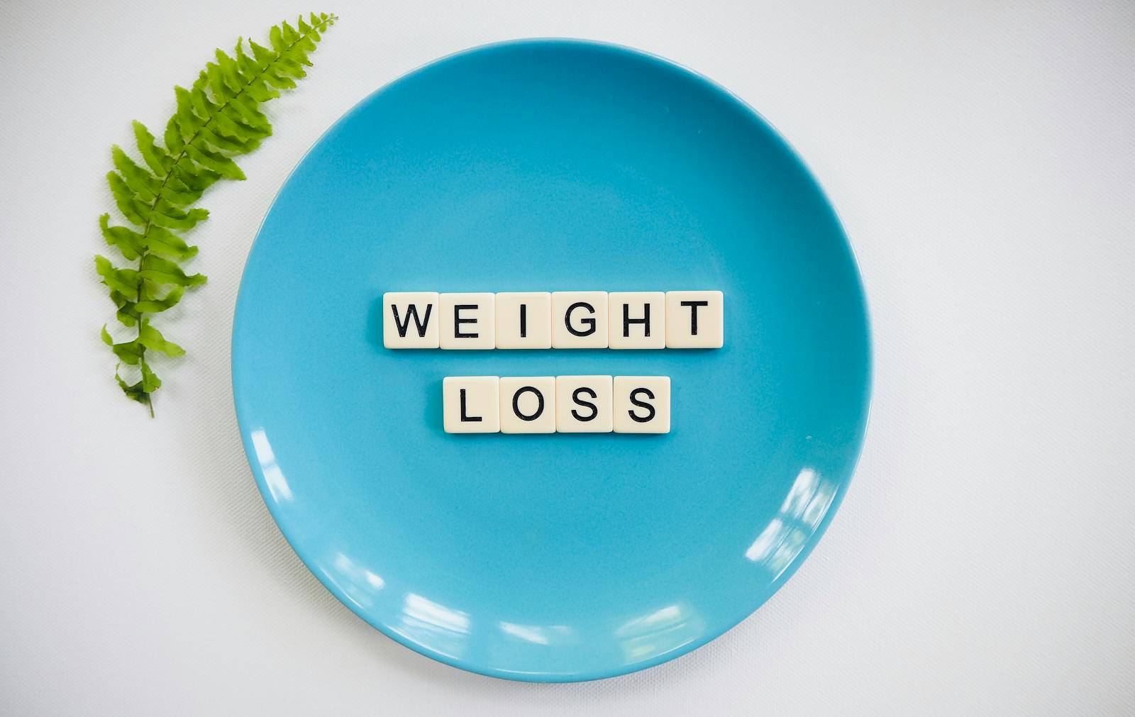 A blue plate with 'weight loss' tiles and a fern leaf on white background.