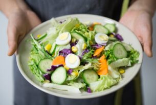 Freshly prepared salad with cucumber, lettuce, carrots, and egg slices presented on a plate.