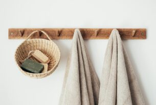 Minimalist bathroom setup featuring eco-friendly wooden hooks, towels, and basket with soap for a sustainable lifestyle.