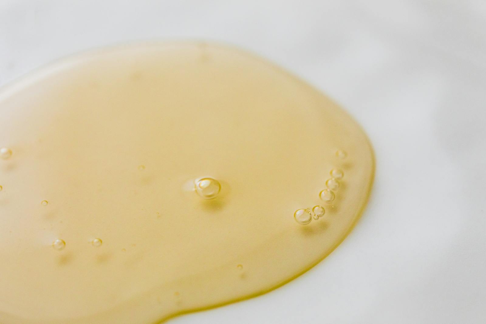 Close-up of a golden liquid with bubbles on a white surface, showcasing beauty and purity.