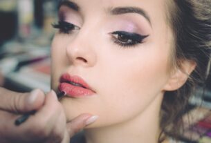 woman getting lips applied with lipstick